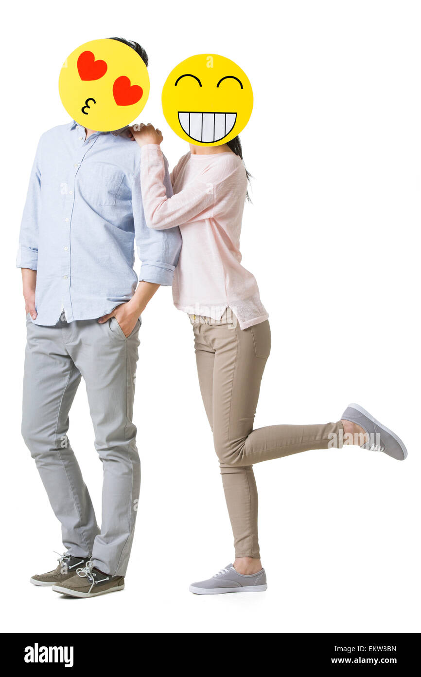 Junges Paar mit Cartoon Emoticon Gesichtern vor den Gesichtern Stockfoto