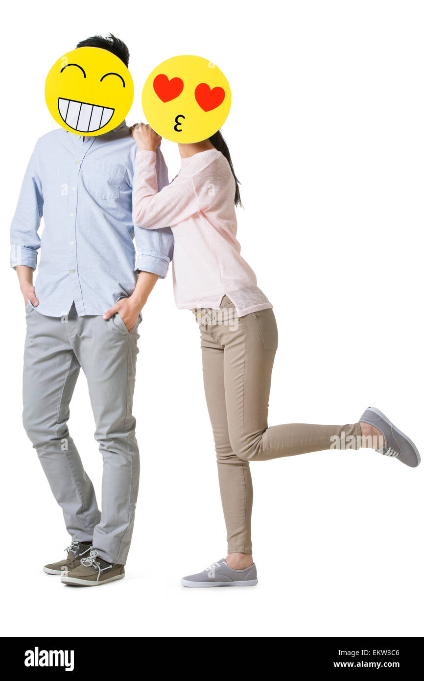 Junges Paar mit Cartoon Emoticon Gesichtern vor den Gesichtern Stockfoto