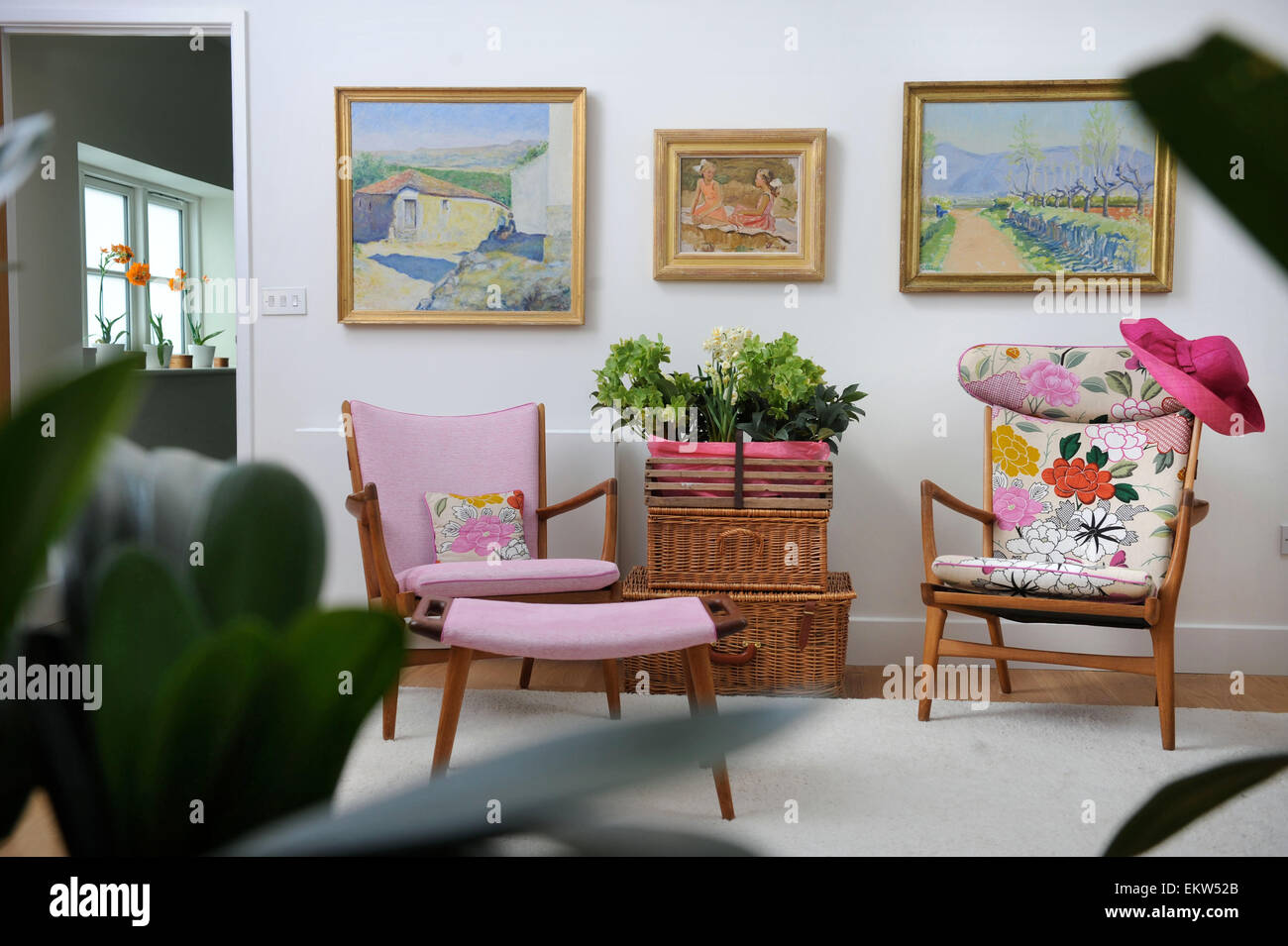 Damen pink Strohhut auf einem Sessel mit Zimmerpflanzen auf Wicker behindert UK angeordnet Stockfoto