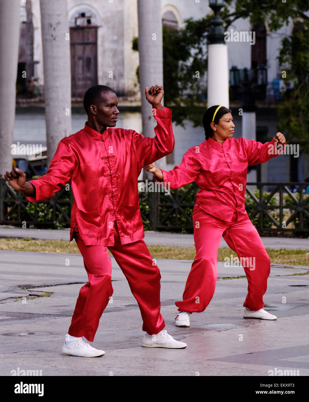 Paar in passenden scharlachrote Tunika einheitliche Durchführung von Tai Chi Übungen in Havanna, Kuba Stockfoto
