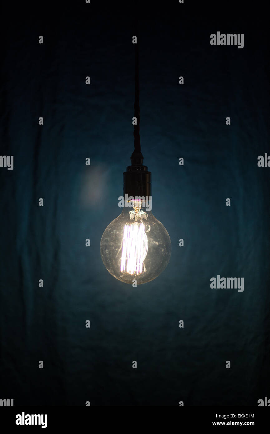 eine Edison Stil Lampe beleuchtet vor einem blauen Hintergrund Stockfoto