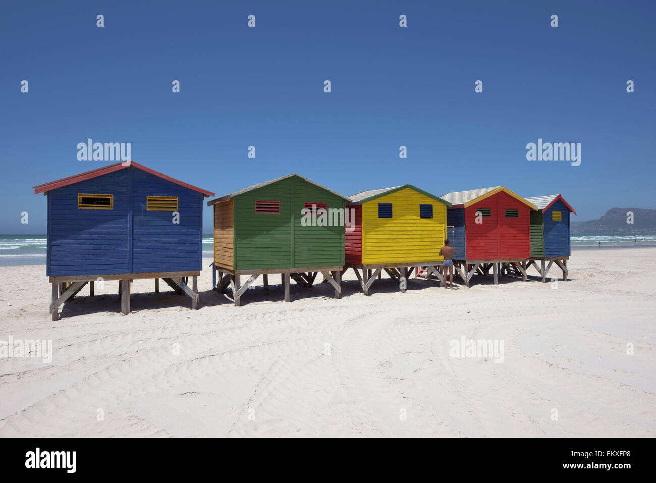 Afrikanischer Mann unter der Dusche vor bunten Baden-Boxen am Strand von St. James, Südafrika Stockfoto