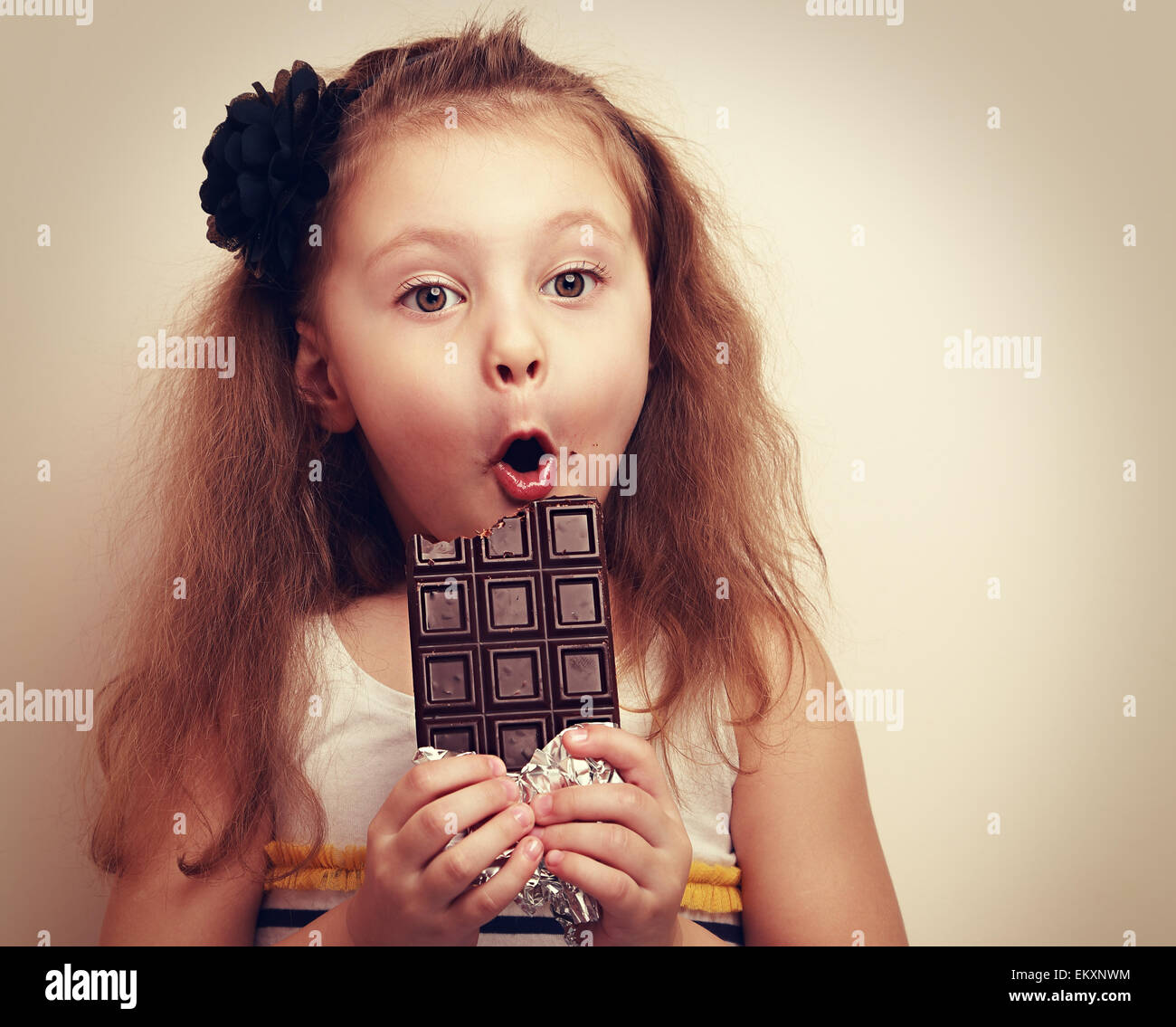 Überrascht, lustiges Mädchen mit offenem Mund und großen Augen halten Schokolade und auf der Suche. Vintage Closeup Portrait mit leeren Textfreiraum Stockfoto