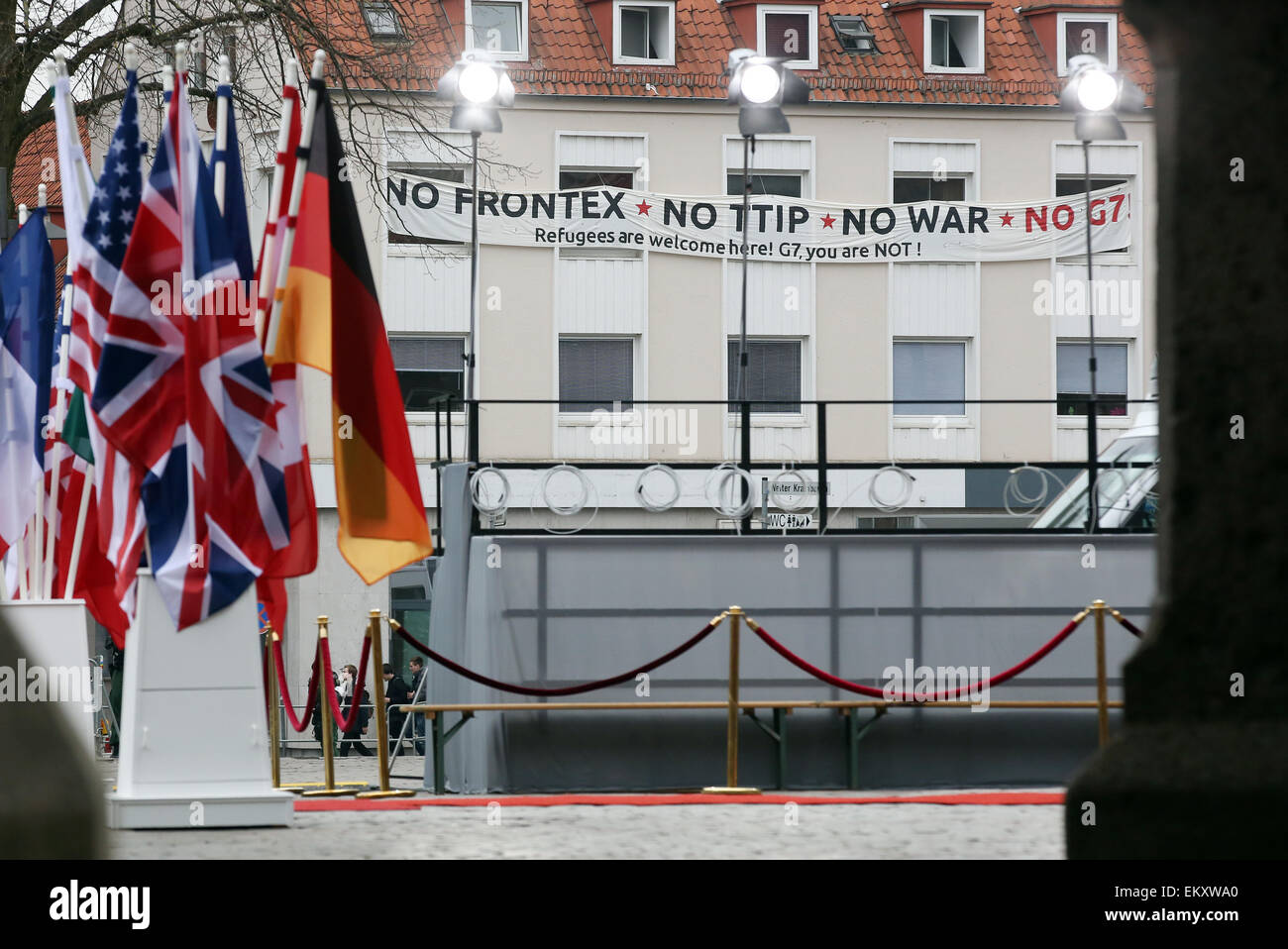 Lübeck, Deutschland. 14. April 2015. Eine Banner-Lesung "Nein Frontex, No TTIP, No War, No G7. Flüchtlinge sind hier willkommen. G7, seid ihr nicht! "ist zu einem Haus hinter dem Rathaus in der Innenstadt von Lübeck, 14. April 2015 beigefügt. Die Flaggen der teilnehmenden Nationen stehen im Vordergrund. Das Treffen der G7-Außenminister wird bei den europäischen Hansemuseum Lübeck vom 14. bis 15. April 2015 stattfinden. Foto: BODO MARKS/Dpa/Alamy Live-Nachrichten Stockfoto