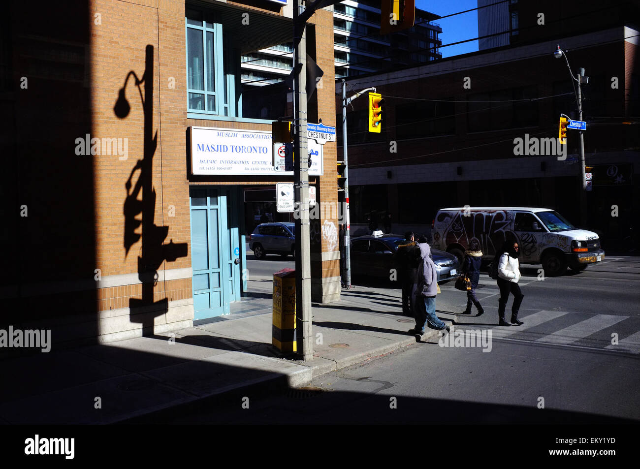 Der Schatten einer Ampel trifft eine Wand, wie Menschen überqueren Sie die Straße in Toronto. Stockfoto