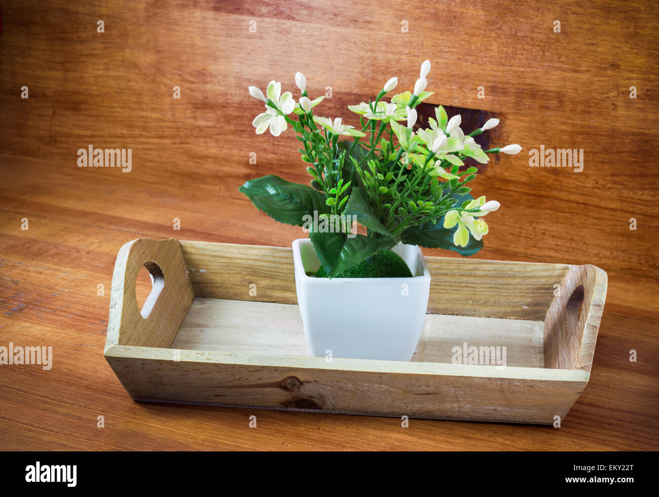 künstliche Blume auf Tablett aus Holz Stockfoto