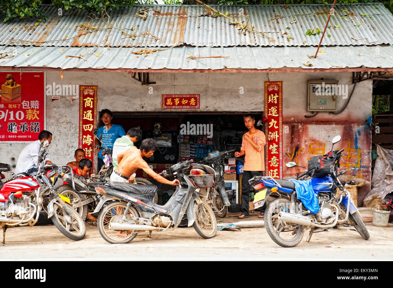 Junge Männer versammeln sich vor einem Gebäude mit ihren geparkten Motorrädern; Ruili Yunnan China Stockfoto