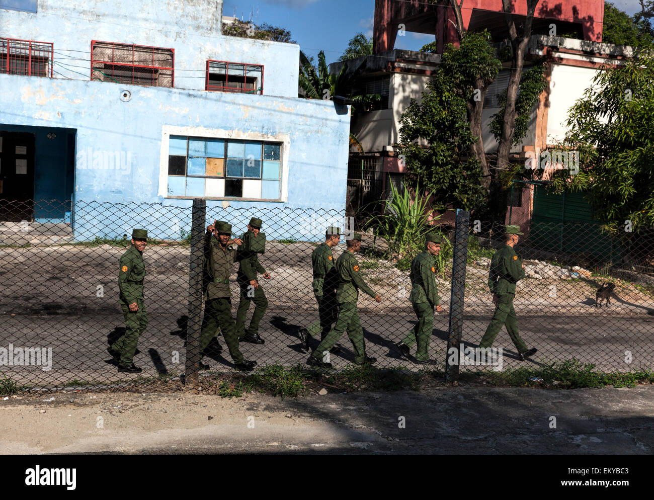 Kubanische Soldaten marschieren, vorbei an einem bunten verfallenen Gebäude in einem abgelegenen Teil von Kuba Stockfoto
