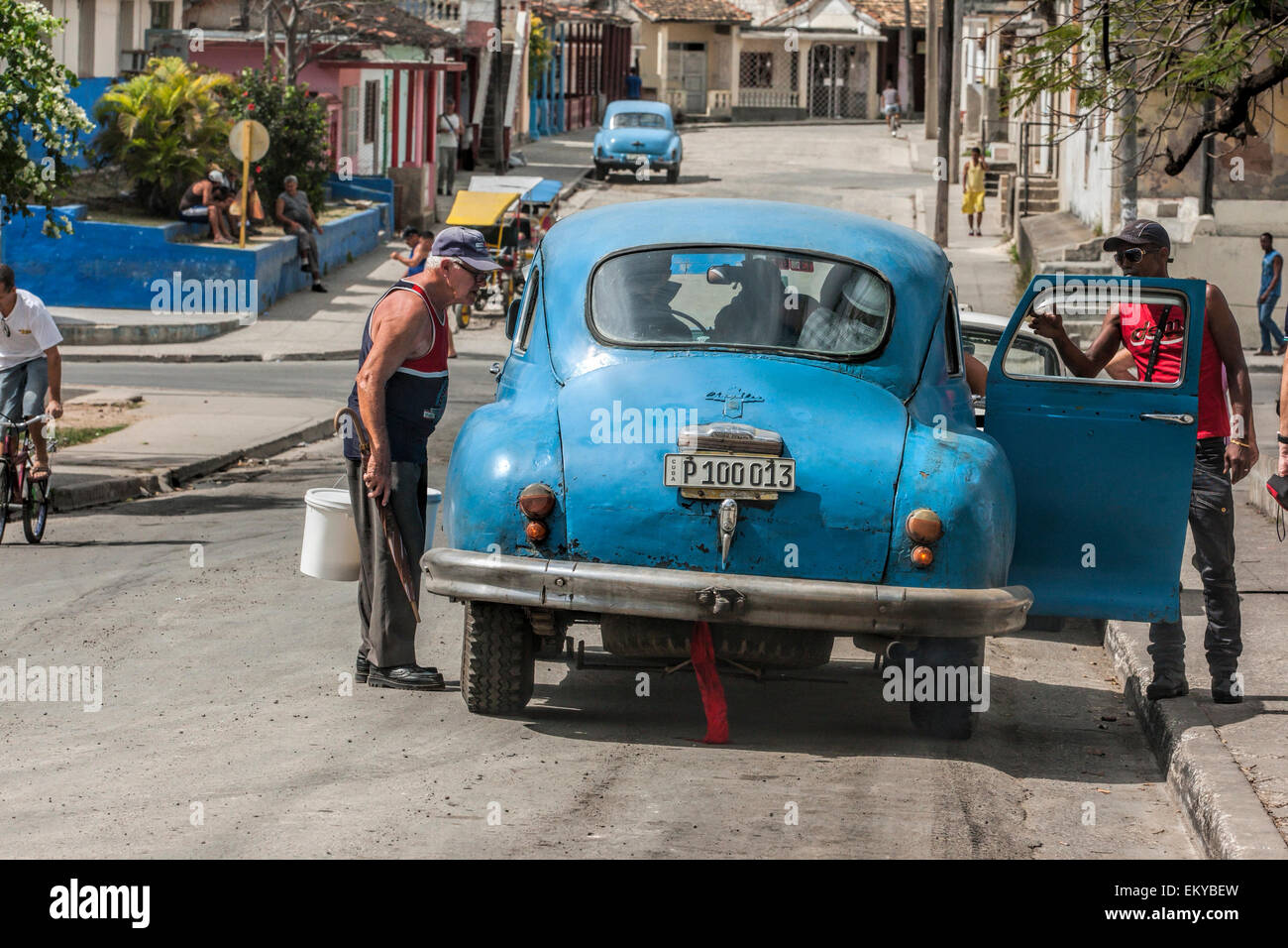 Alte amerikanische blaues Auto von hinten. Dieses Auto hat einen großen Öl-Leck. Kubanische Männer betrachten das Auto. Stockfoto