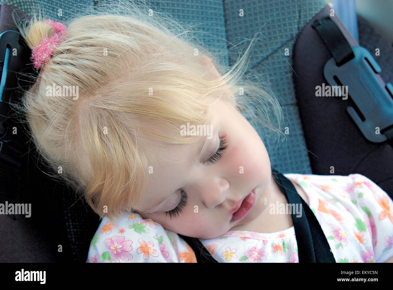Kleine blonde kaukasische Mädchen schlafen in einem Autositz. Stockfoto