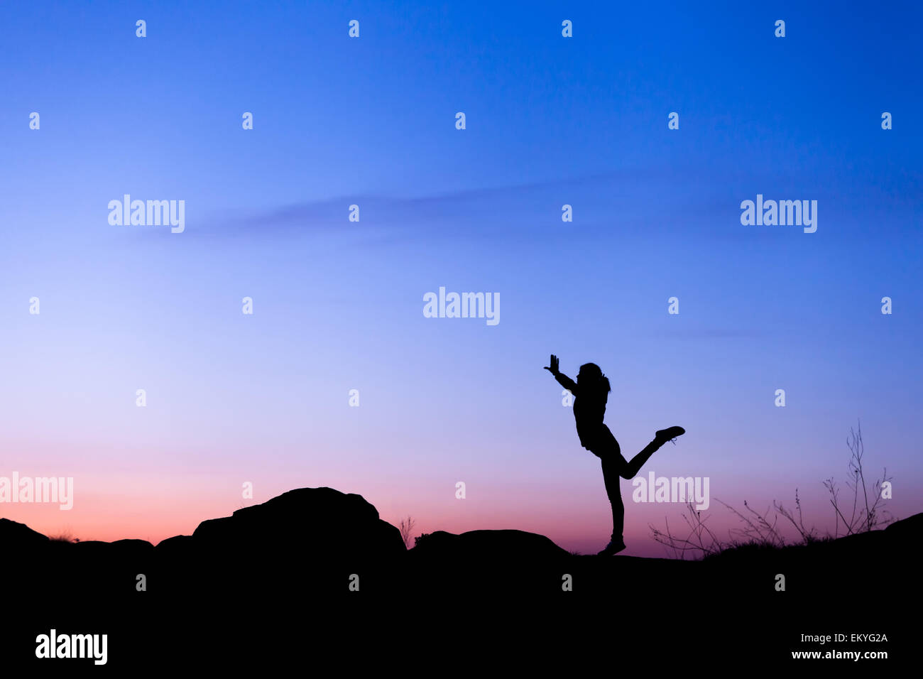 Silhouette der glückliche junge Frau mit gegen schönen bunten Himmel erhobenen Armen. Sommer Sonnenuntergang. Landschaft Stockfoto