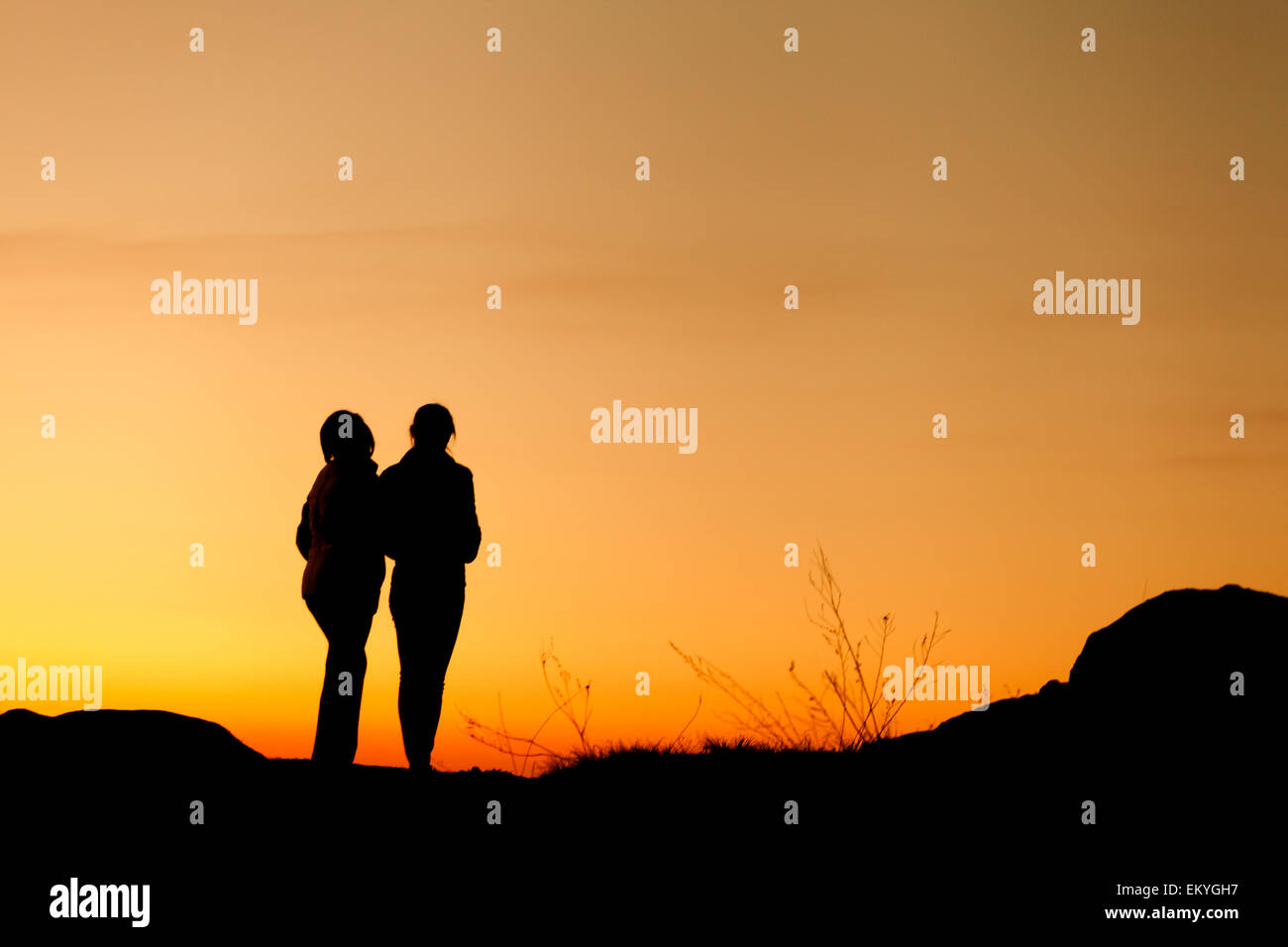 Silhouetten von Mutter und Tochter an den wunderschönen Sonnenuntergang. Einbruch der Dunkelheit. Sommerlandschaft Stockfoto