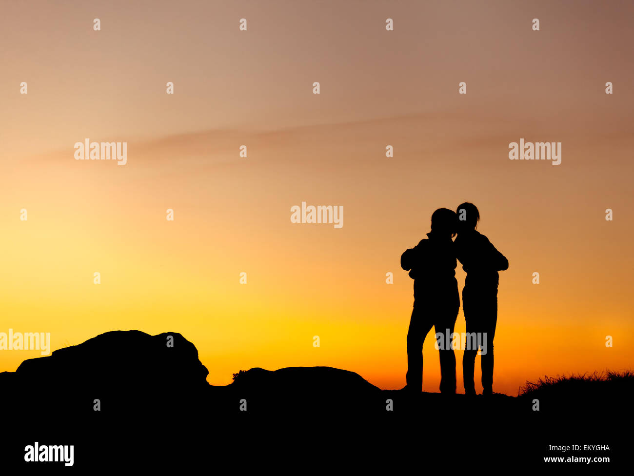 Silhouetten von Mutter und Tochter an den wunderschönen Sonnenuntergang. Einbruch der Dunkelheit. Sommerlandschaft Stockfoto