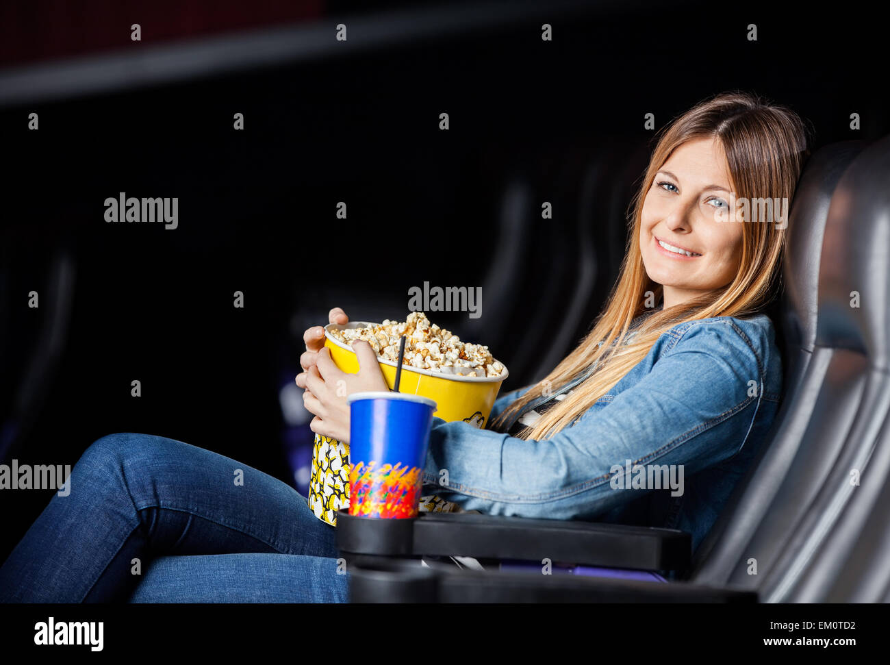 Lächelnde Frau mit Snacks im Kino Stockfoto