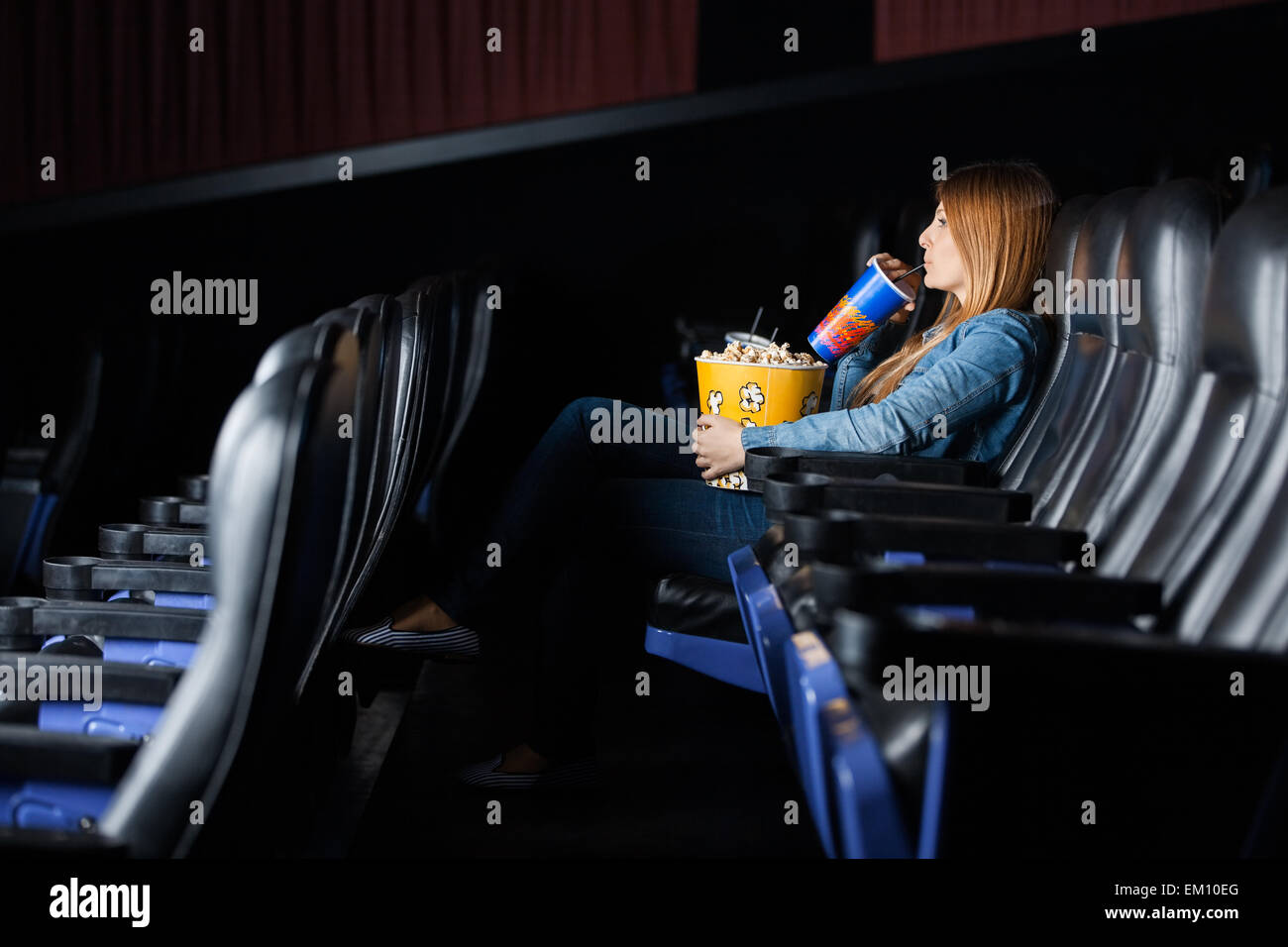 Frau trinkt Cola bei Film im Theater Stockfoto
