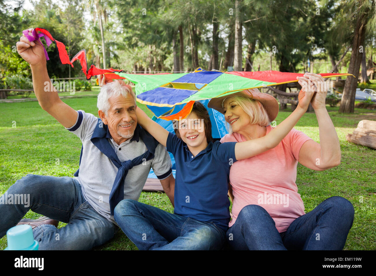 Fröhlicher Junge mit Großeltern halten Kite auf Campingplatz Stockfoto