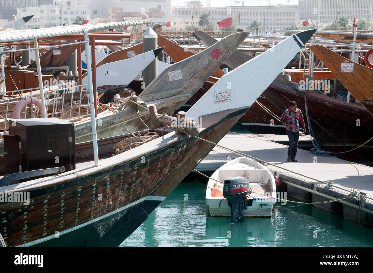 Ein Mann geht die inmitten von traditionellen Dhau Boote am Kai in Doha, Katar. Stockfoto