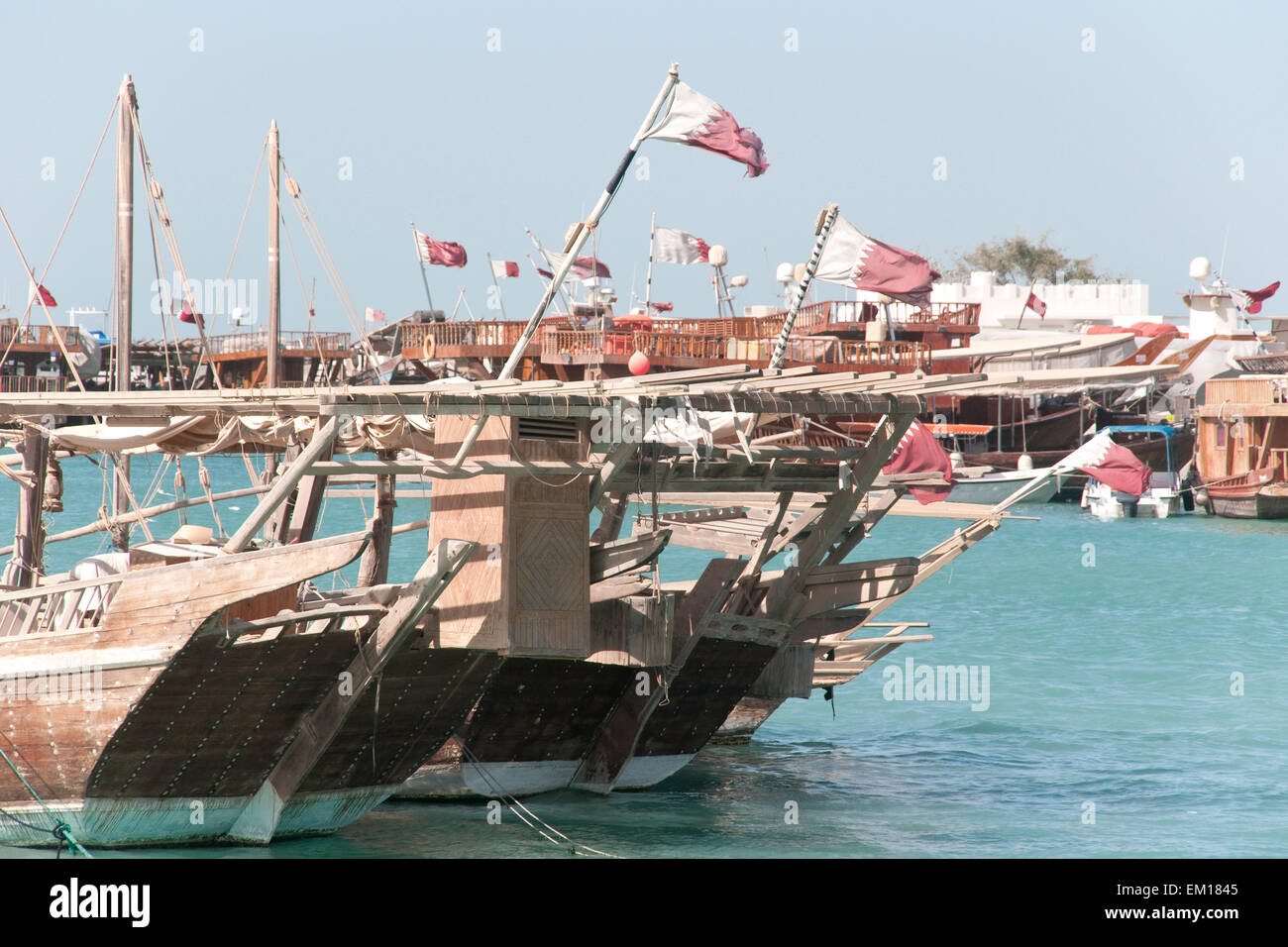 Traditionellen hölzernen Dhau Boote gekrönt von Katar Fahnen und vertäut in einem Dhau-Kai in der Stadt von Doha, Katar. Stockfoto