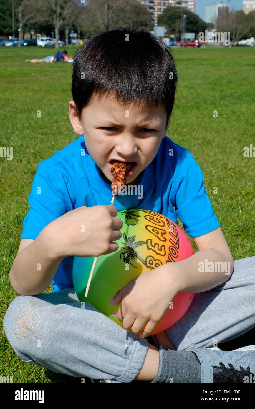 junge genießt essen Huhn Sate bei einem Picknick an einem herrlich sonnigen Nachmittag in Southsea common England uk Stockfoto