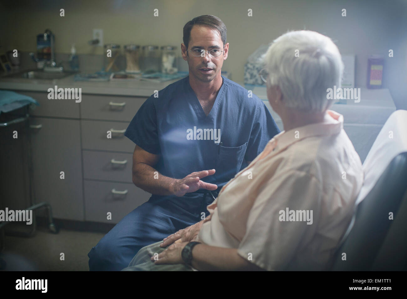 Ein Arzt besprechen einen Punkt mit seinem Patienten, die vor ihm sitzt. Stockfoto