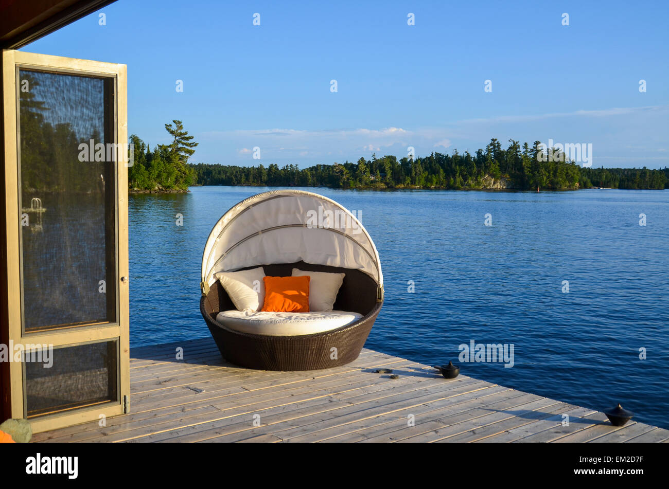 Eine gepolsterte Sessel auf einem hölzernen Dock am Rand des Wassers; Lake Of The Woods Ontario Kanada Stockfoto