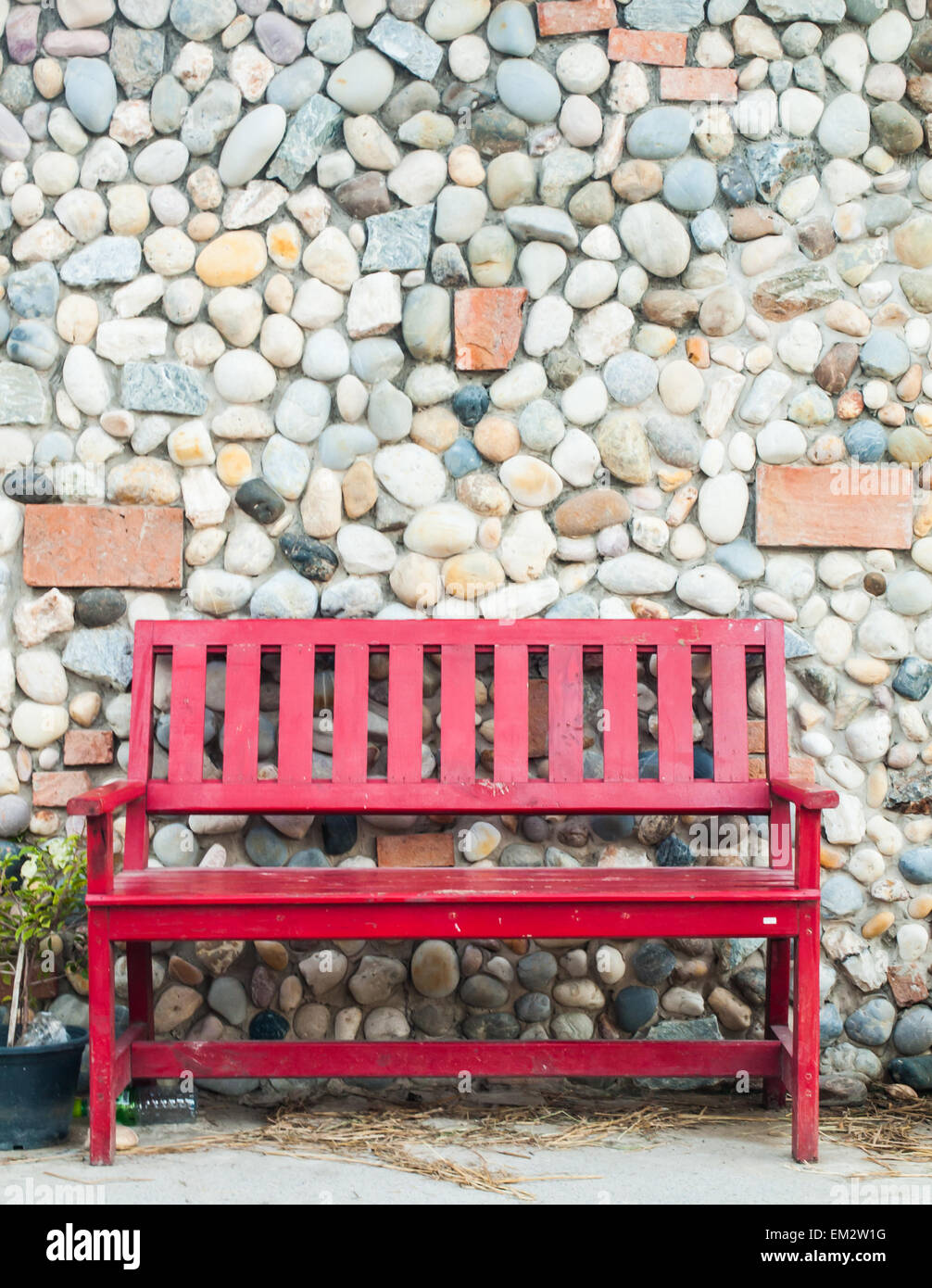 rote Sitzbank aus Holz und Stein wallbackground Stockfoto