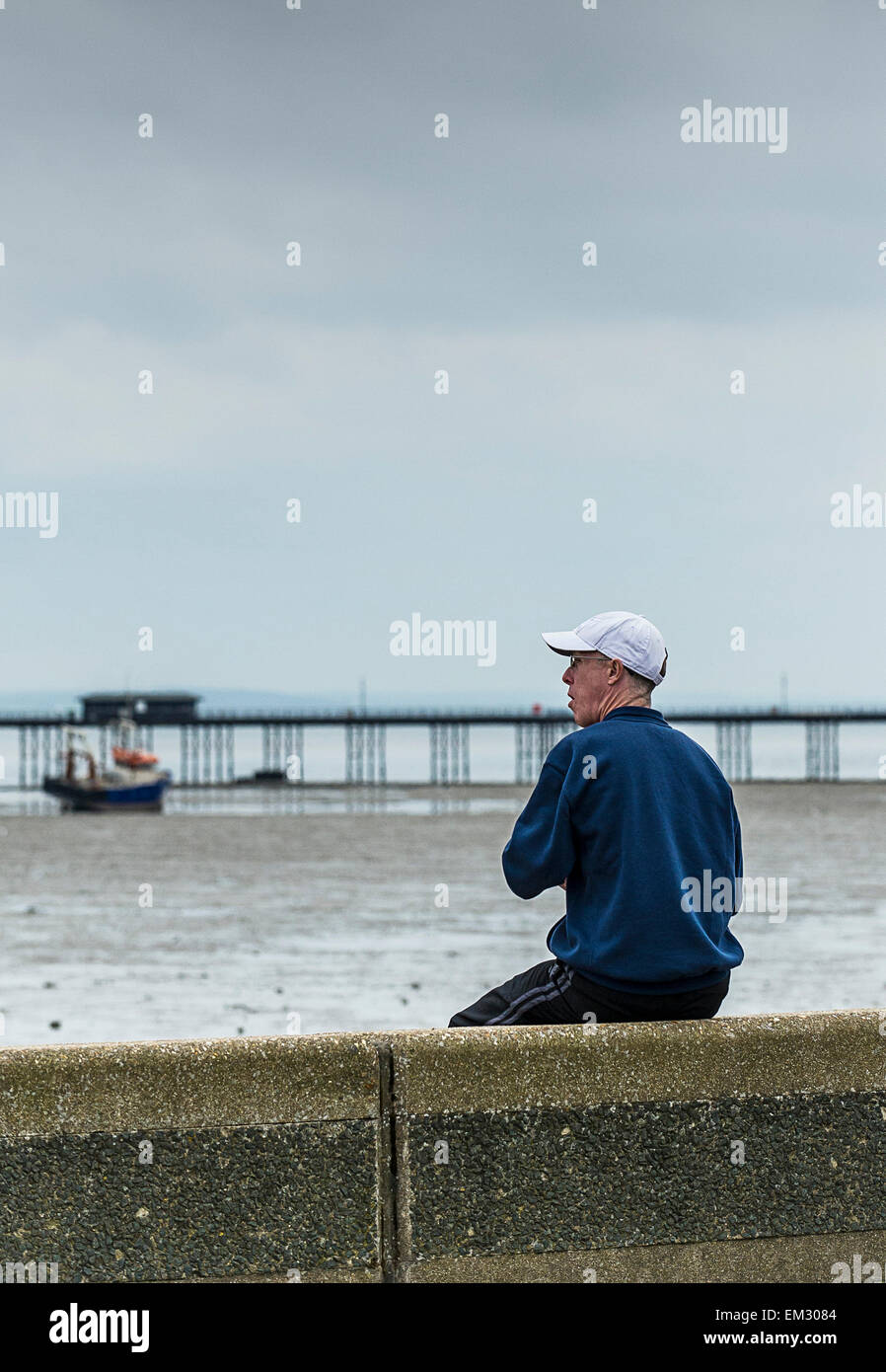 Ein Mann sitzt auf seinem eigenen auf Southend direkt am Meer. Stockfoto