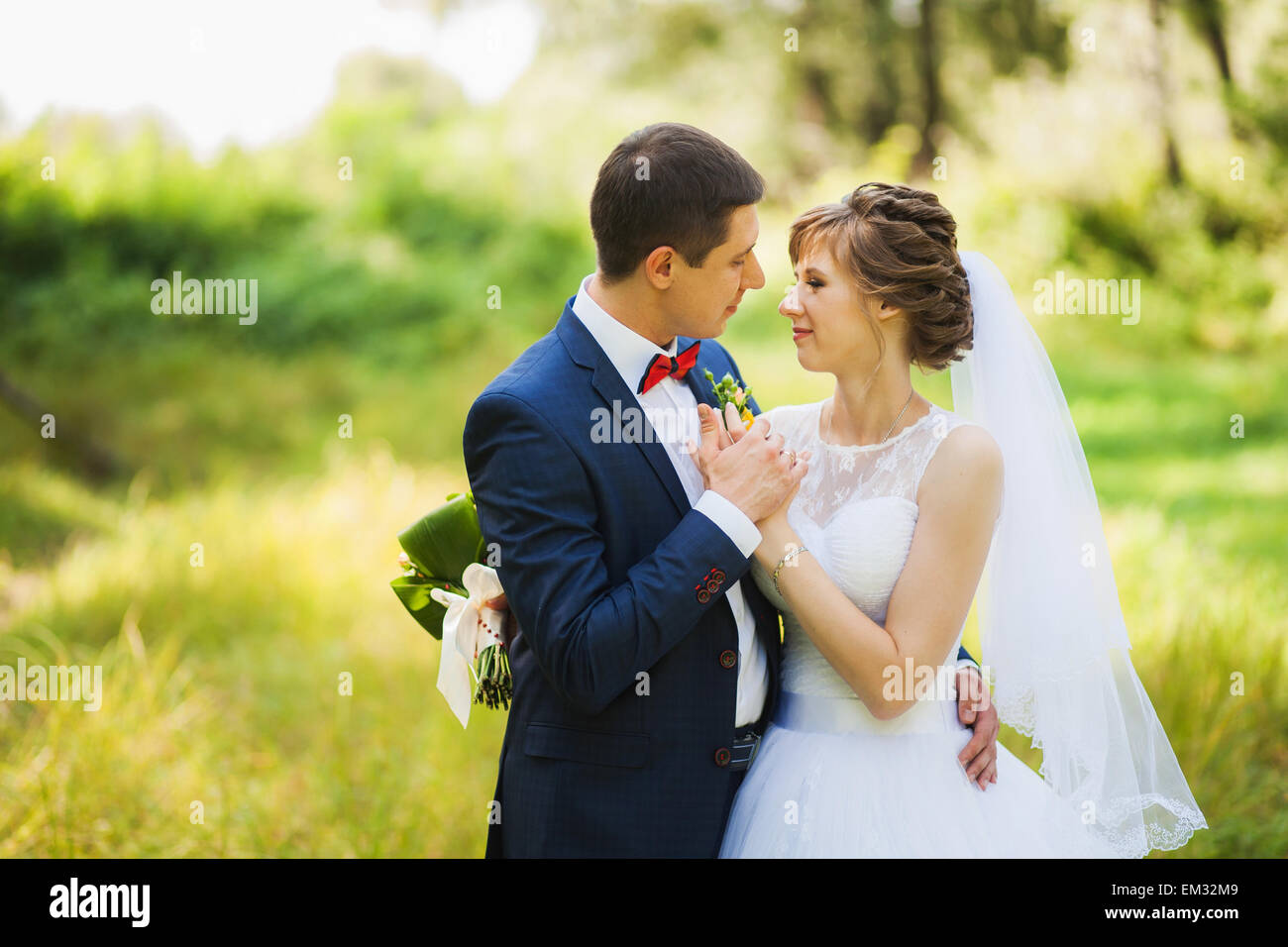 glückliche Braut, Bräutigam stehen im grünen Park, küssen, Lächeln, lachen, umarmen. Liebhaber in Hochzeitstag. Stockfoto