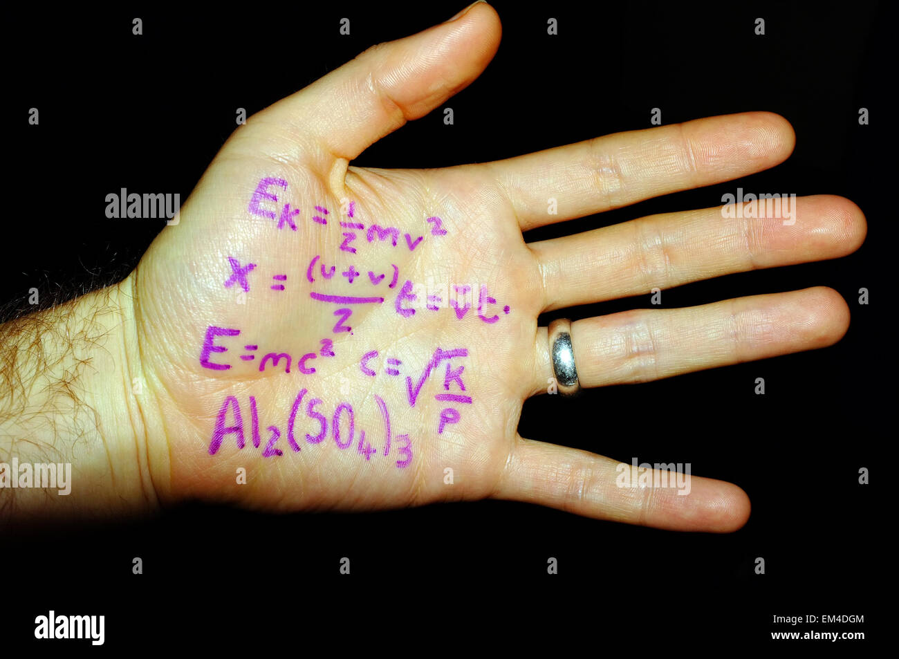 Physik Formeln auf einen weißen Mann Hand fotografiert vor einem schwarzen Hintergrund geschrieben. Stockfoto