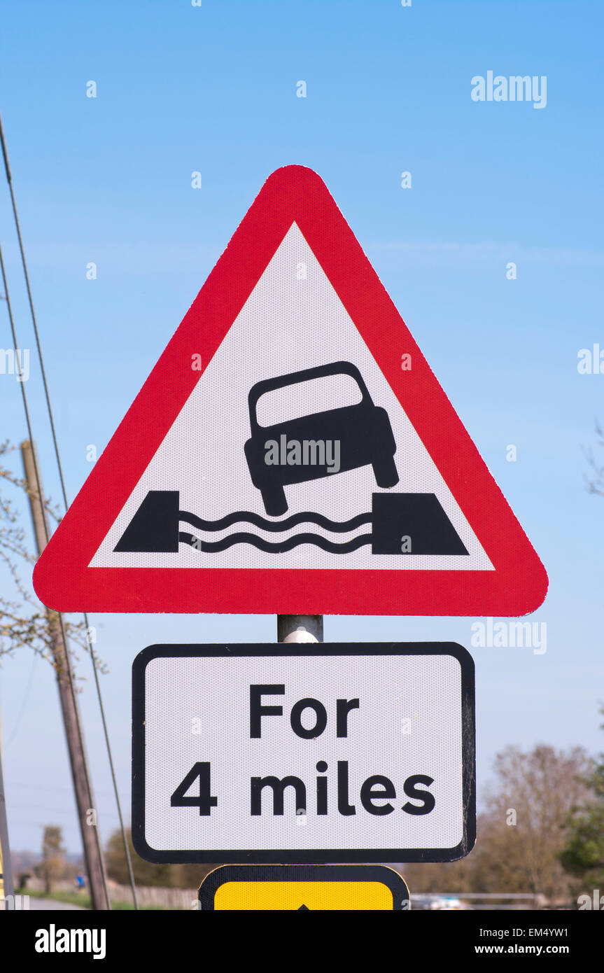 Wasserlauf neben Road Ahead Verkehr Warnzeichen UK Stockfoto