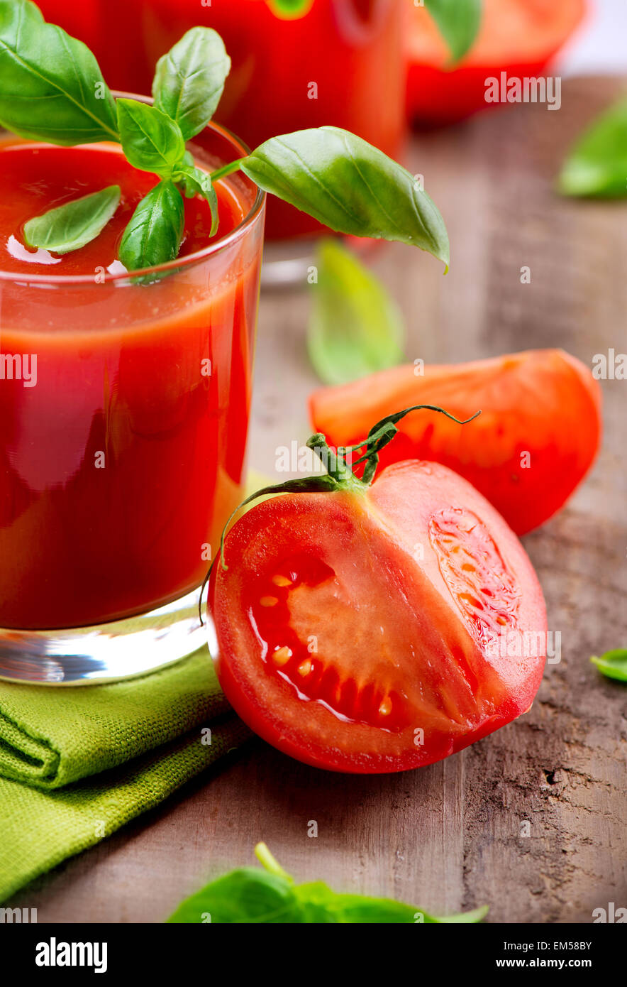 Tomatensaft und frischen Tomaten mit Basilikum auf einem Holztisch Stockfoto