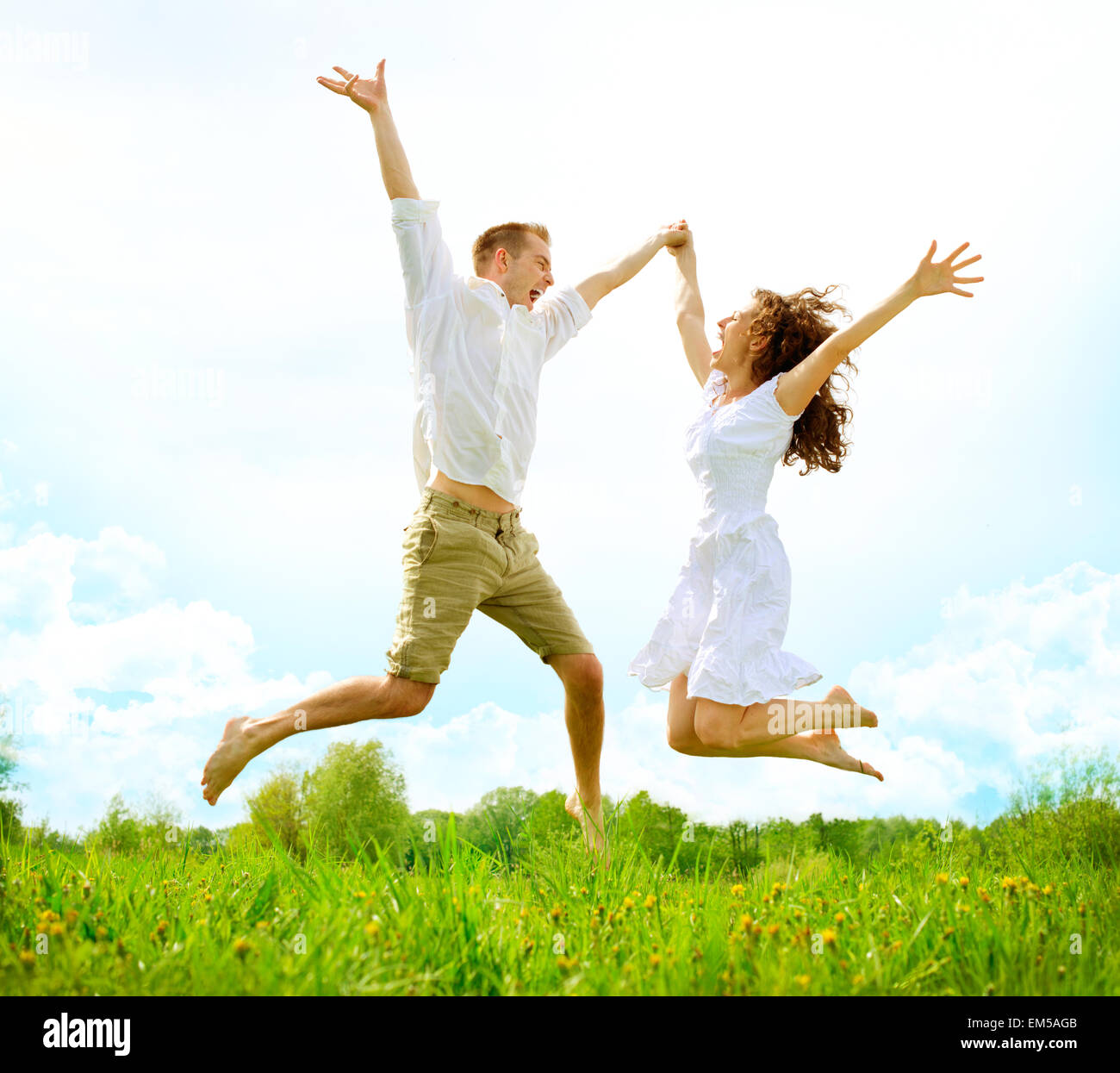 Glückliches Paar im Freien. Familie springen auf der grünen Wiese Stockfoto