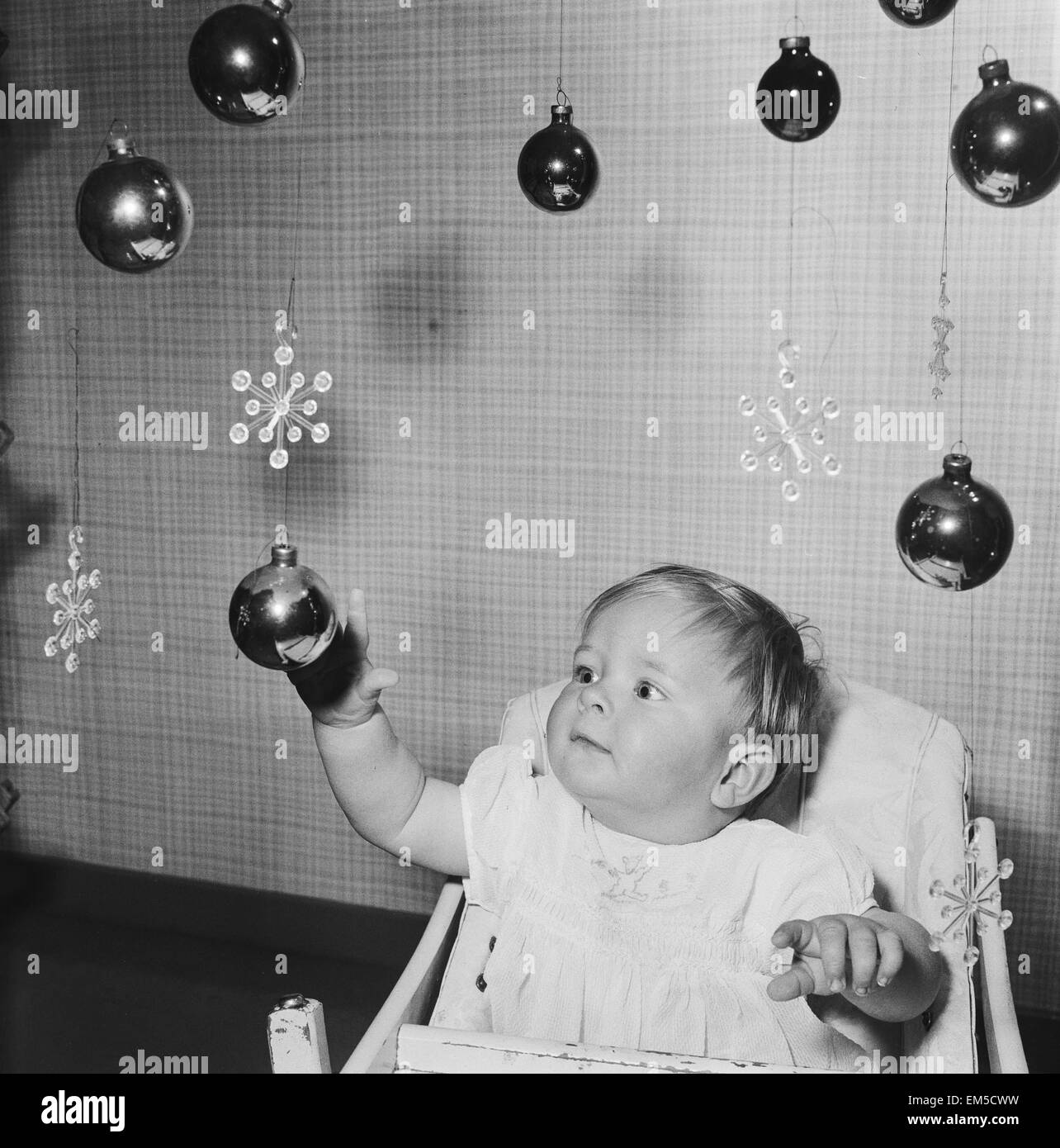 10 Monate alten vavy jungen Christopher Trayhorn von Stevenage Neustadt spielen mit Kugeln hängen, wie er sich auf sein erstes Weihnachten freut. 5. Dezember 1958. Stockfoto