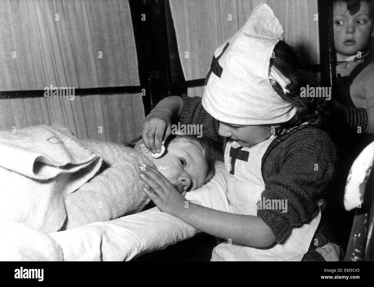 Drei Jahre alte Brenda Aukett geprüft von Schwester Janice Garry, 5 Jahre, so sie eine Partie von Krankenschwestern und Patienten an Kintore Weg Nurseery Schule in Bermondsey spielen. 14. Januar 1955. Stockfoto