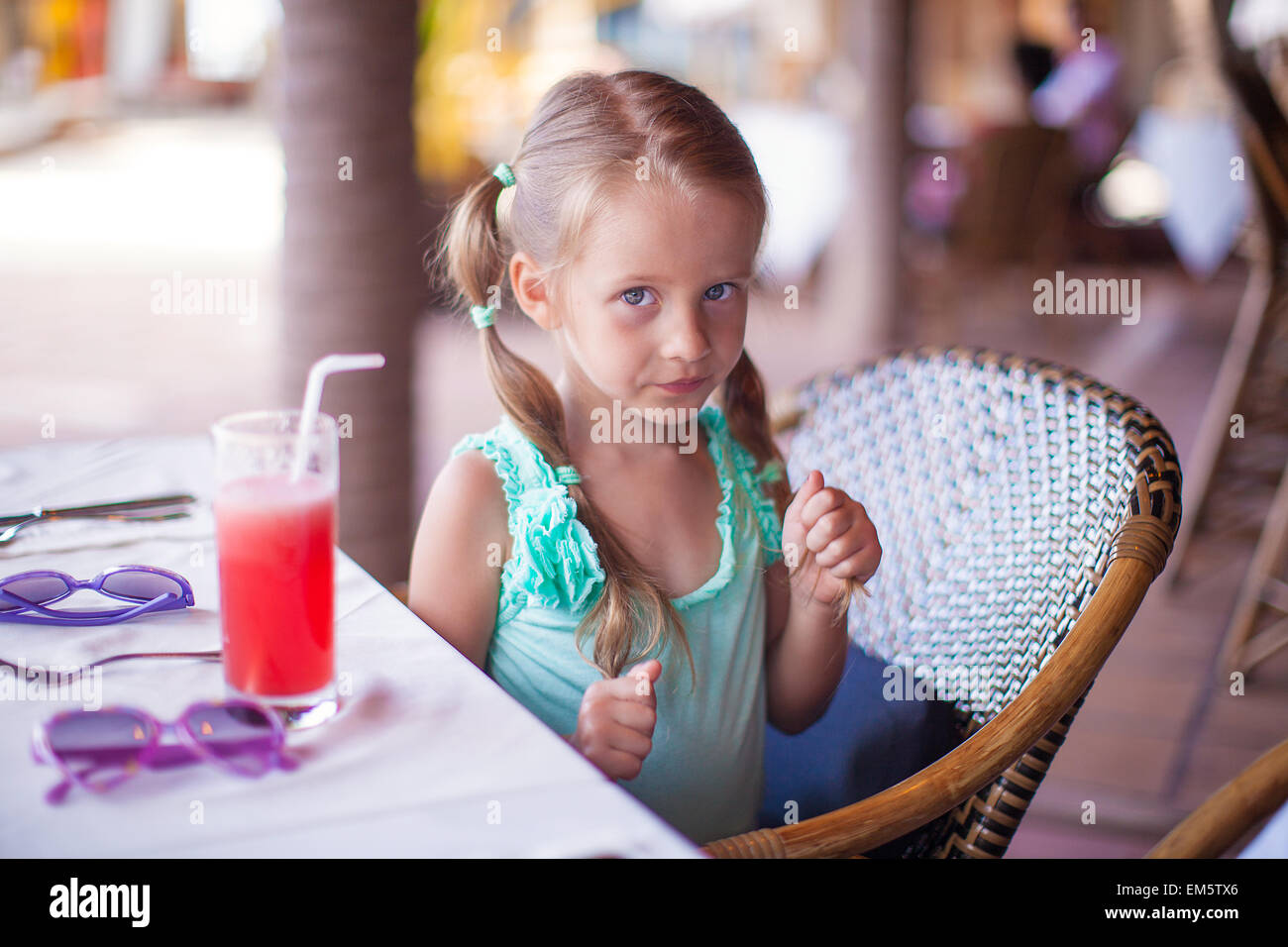 Kleines Mädchen sitzt im Stuhl im Restaurant warten auf ihr Essen Stockfoto