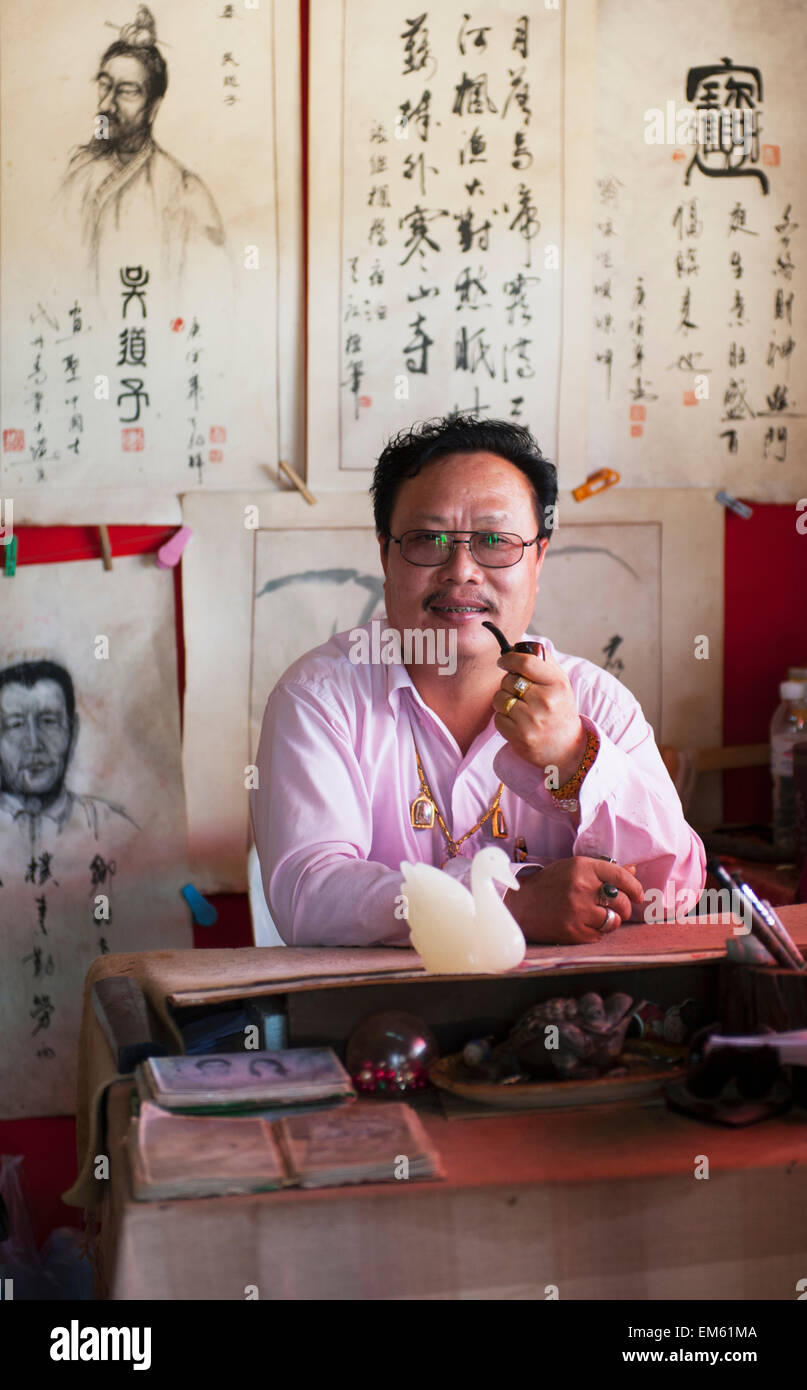 Thailand, Mann Pfeife beim Sitzen am Schreibtisch im chinesischen Dorf in der Nähe von Pai; Shandicun Stockfoto