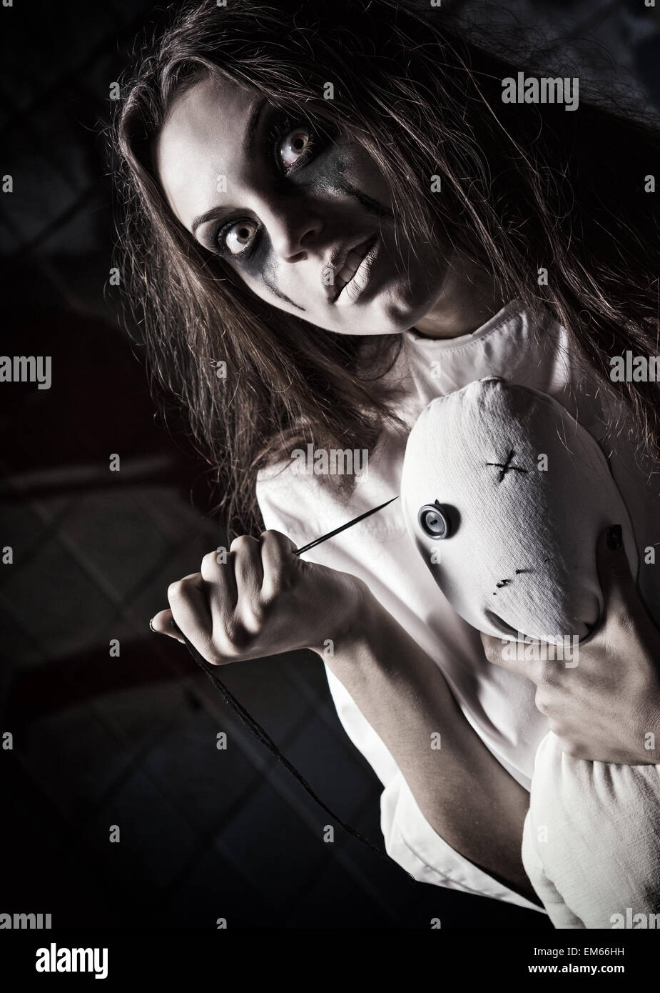 Horror-Stil gedreht: unheimlich verrückte Mädchen mit Mizzi Puppe und Nadel in Händen Stockfoto