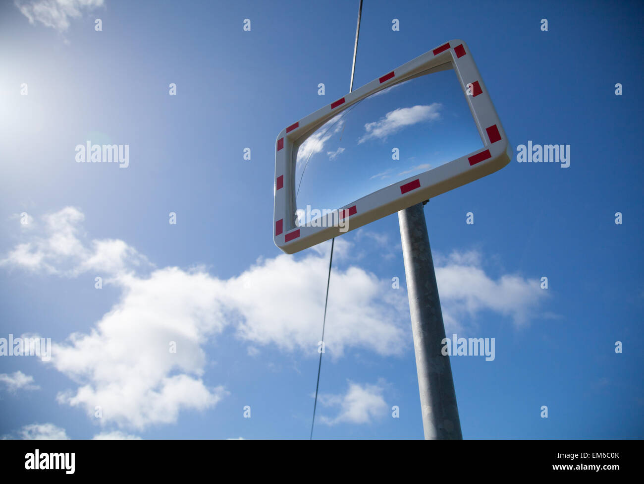 Kreative Schuss von einem Verkehrsspiegel Mastleuchte an einer Straßenkreuzung erschossen vor blauem Himmel mit Sonne und einige Wolken Stockfoto