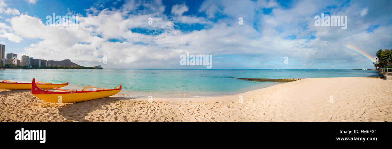 Waikiki, Hawaii, Oahu, Outrigger-Kanus am Strand mit einem Regenbogen und Diamond Head im Hintergrund. Stockfoto