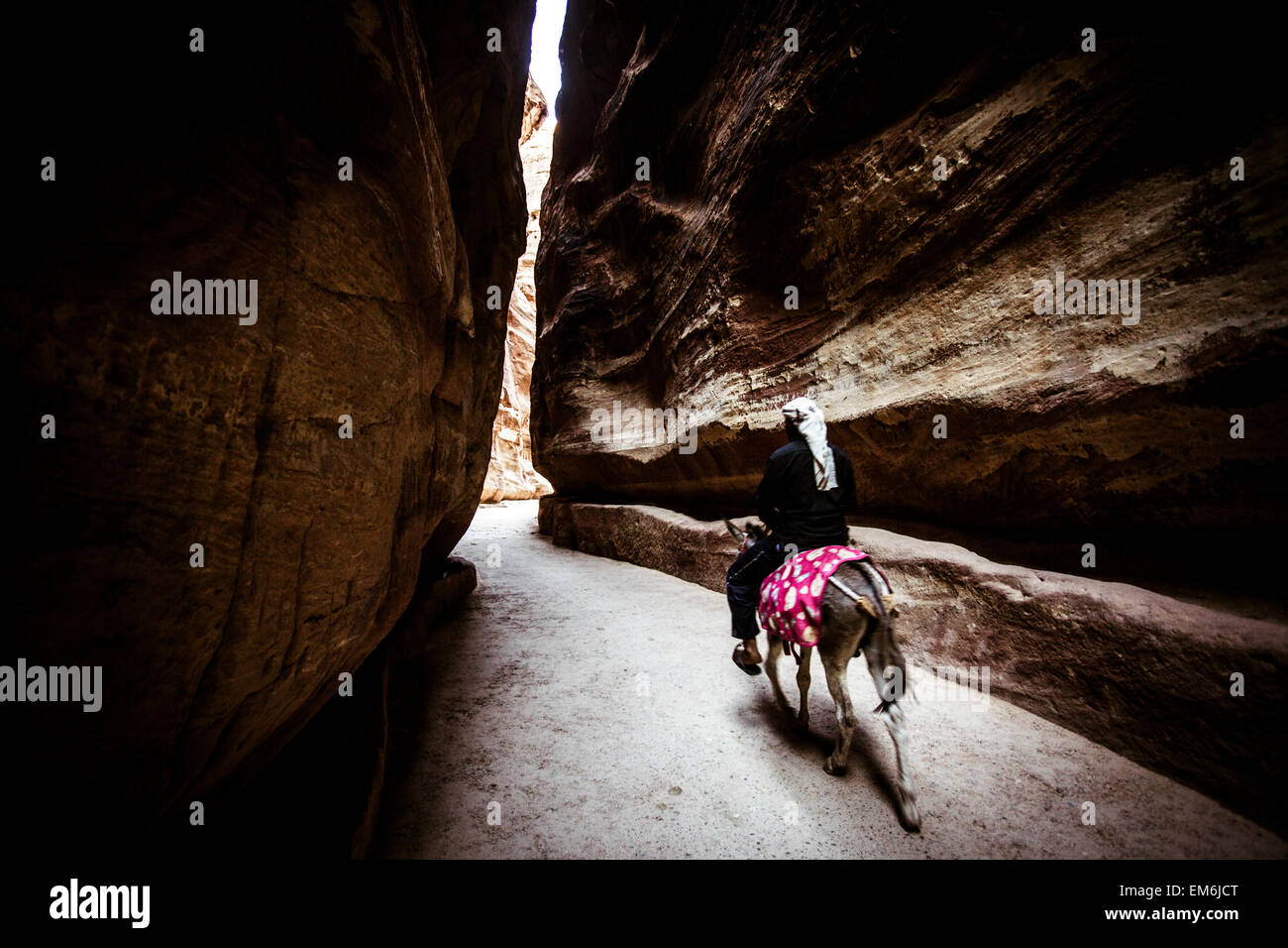 Mann auf einem Esel durch den Siq in Petra, Jordanien Stockfoto