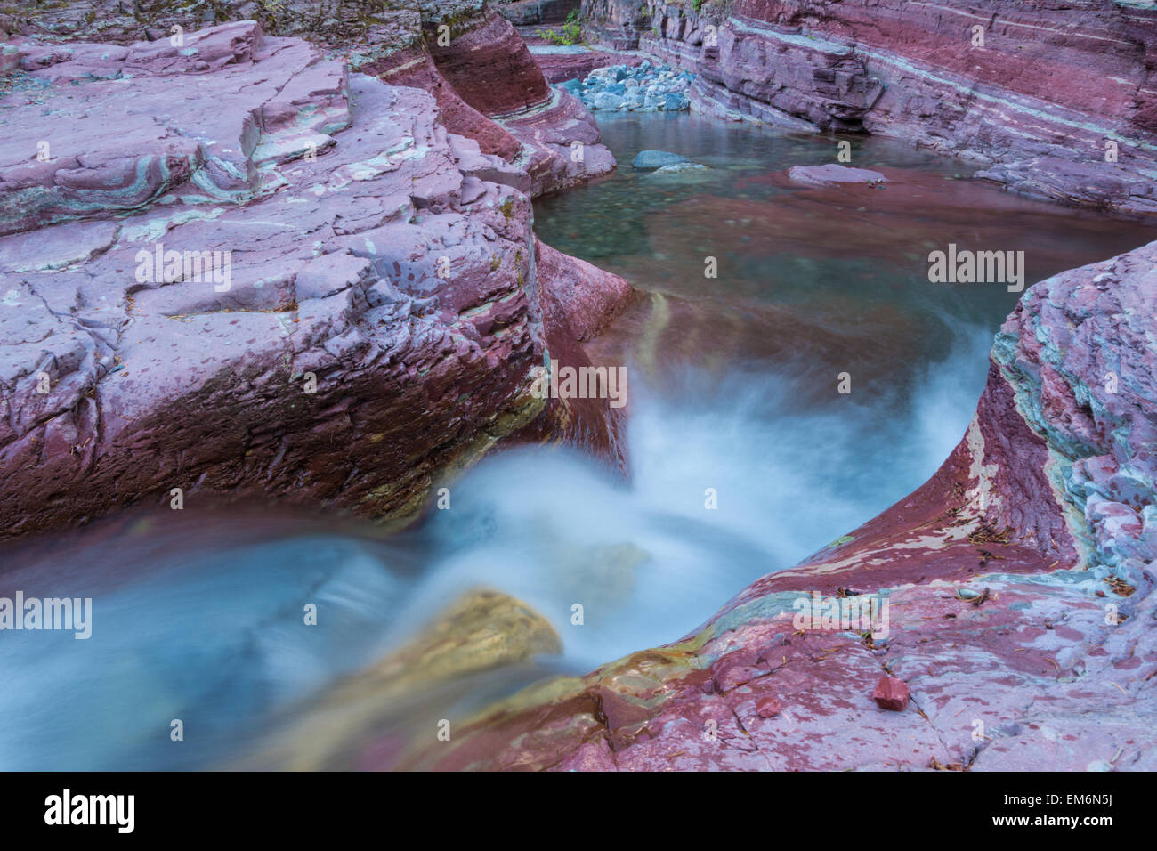 Herabstürzende Wasser hinunter eine red Rock Canyon, Waterton Lakes Nationalpark, Alberta Stockfoto