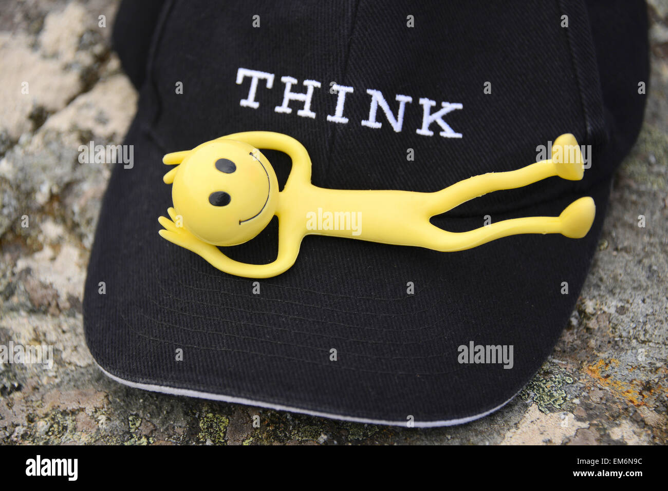 Gelbe Smiley Mann auf Urlaub in den Äußeren Hebriden - Hier ist er bequem auf eine schwarze Baseball cap mit dem Wort denken Stockfoto
