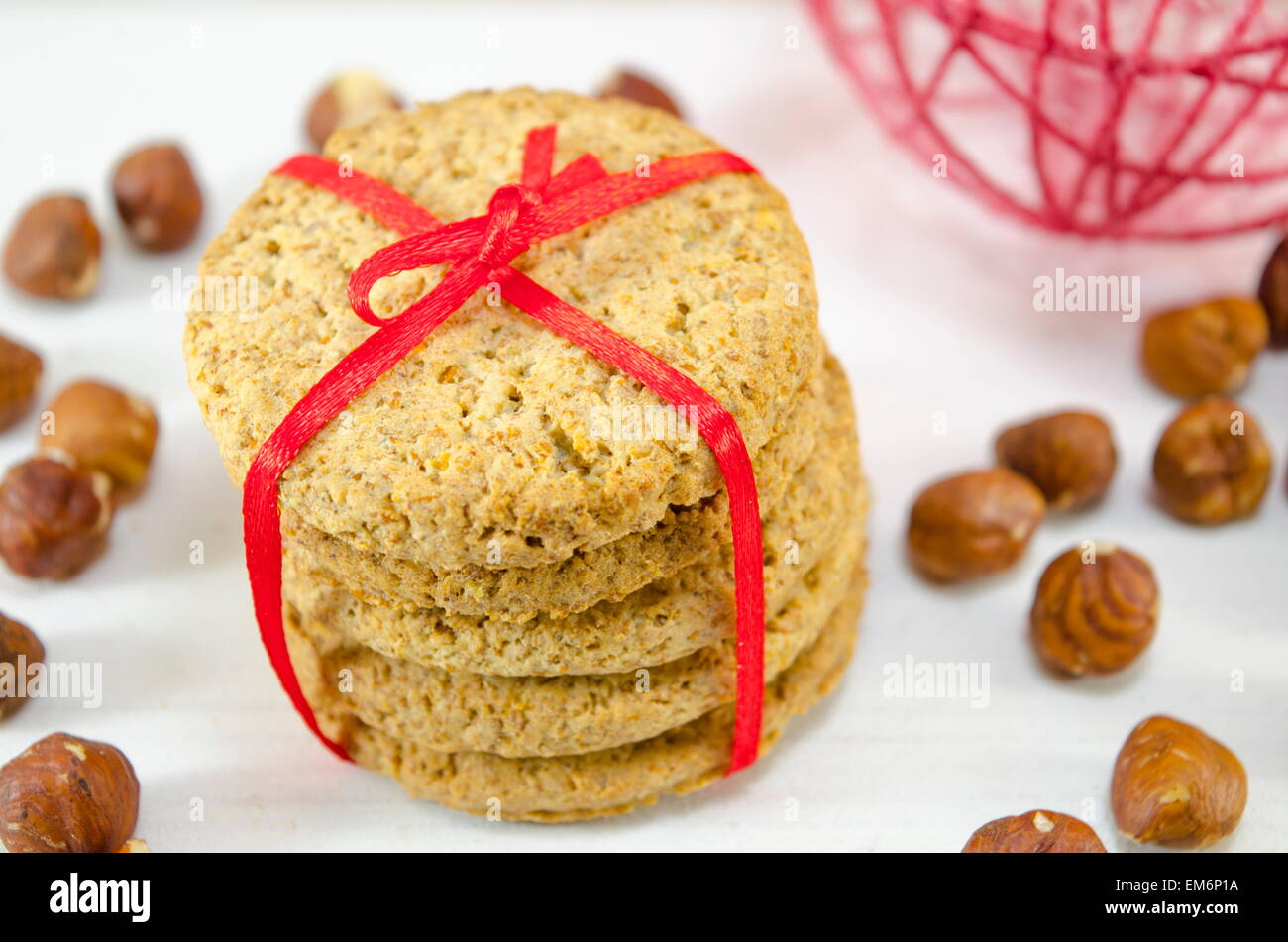 Reihe von integralen Cookies gebunden mit einem roten Band umgeben mit rohen Nüssen Stockfoto