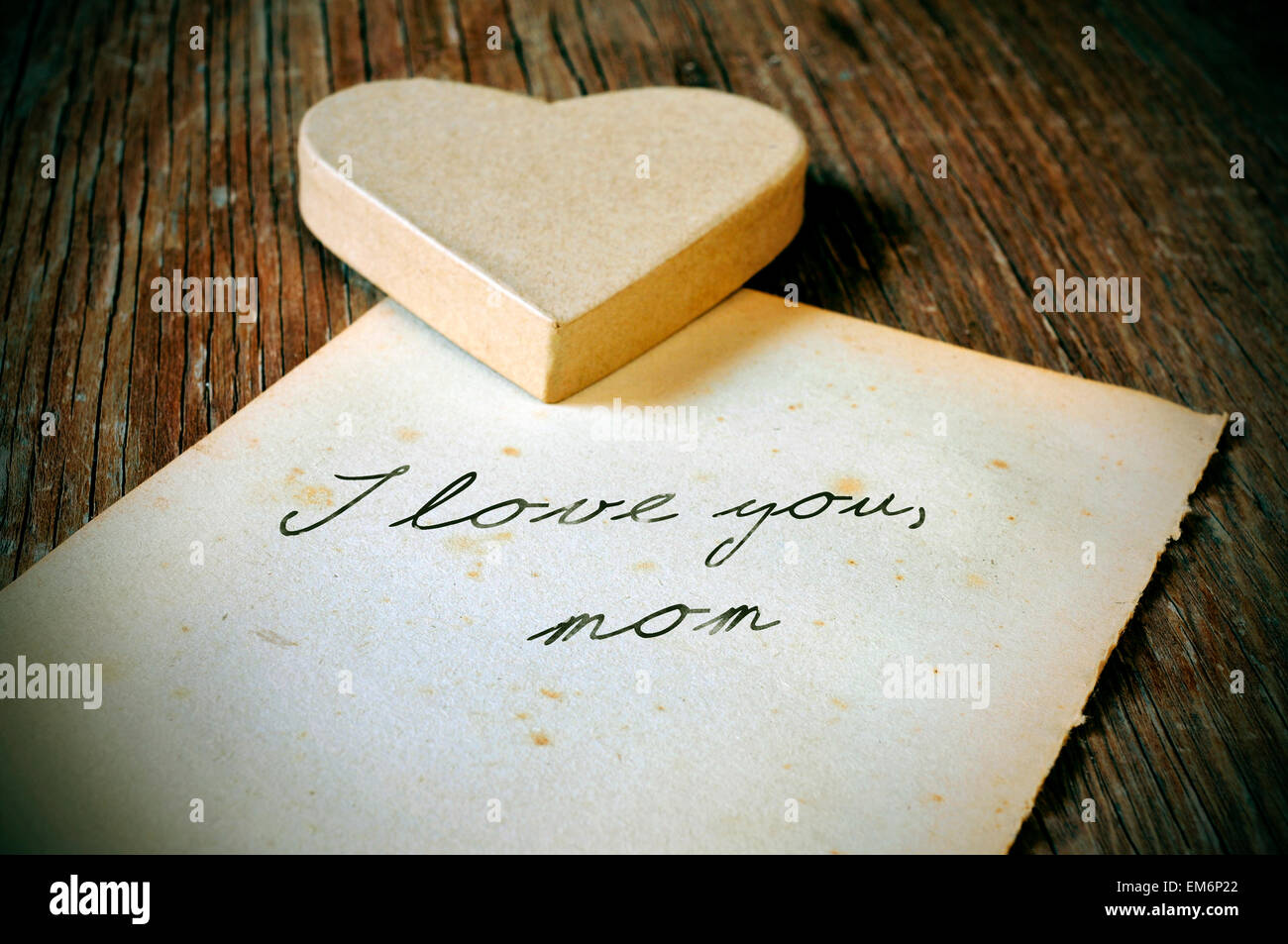 einen Karton Herz und alten Blatt Papier mit dem Text ich dich Mama geschrieben auf einem rustikalen Holztisch mit einem Retro-e Liebe Stockfoto