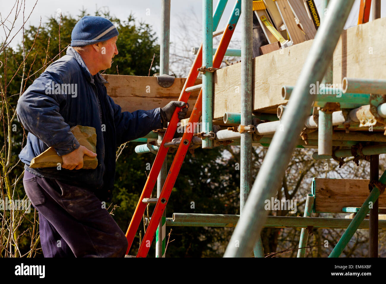 Generator auf einer Leiter arbeiten auf einer Baustelle mit Gerüststangen und Stein Mauerwerk Stockfoto