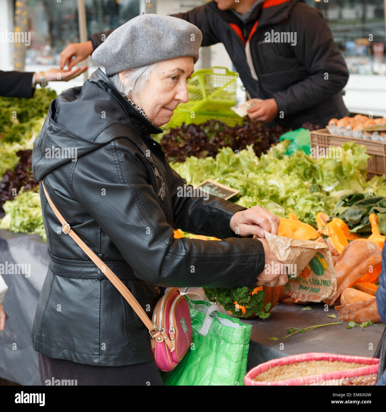 Ältere Dame Gemüse in einem französischen Markt zu kaufen.  Die senior Französin trägt eine Baskenmütze. Stockfoto