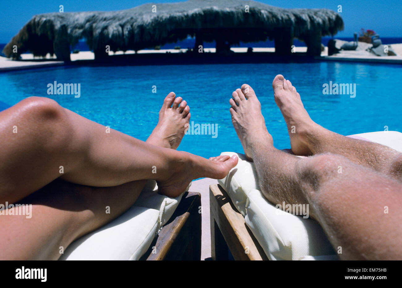 Mexiko, Cabo San Lucas, Terrasol Resort, Leute, Sonnenbaden am Pool liegen, Beine und Füße. Stockfoto