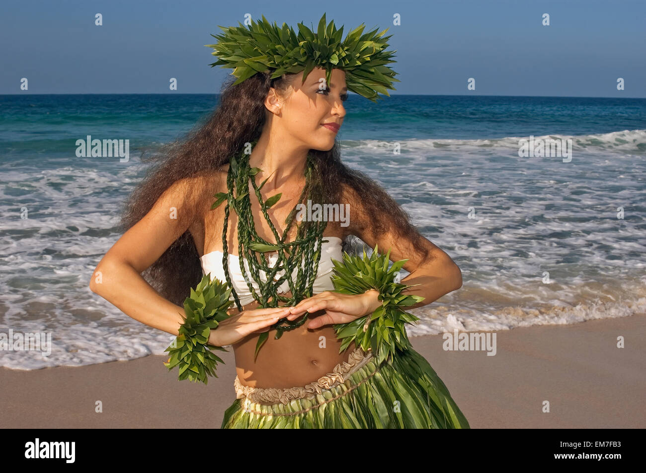 Hula-Tänzerin In Ti-Blatt Rock, Haku, Lei, In einer tänzerischen Pose am Strand Stockfoto