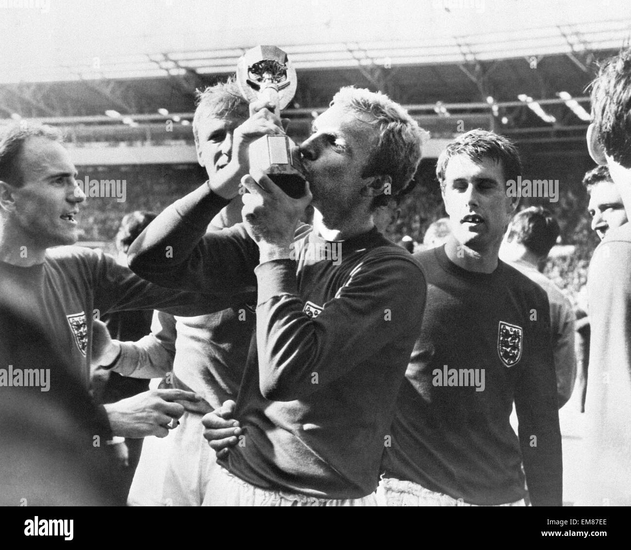 Fußball World Cup-Finale 1966 England 4 Westdeutschland 2 im Wembley-Stadion. England-Kapitän Bobby Moore küsst den Pokal von Teamkollegen George Cohen, Jack Charlton und Geoff Hurst beobachtet. 30. Juli 1966. Stockfoto