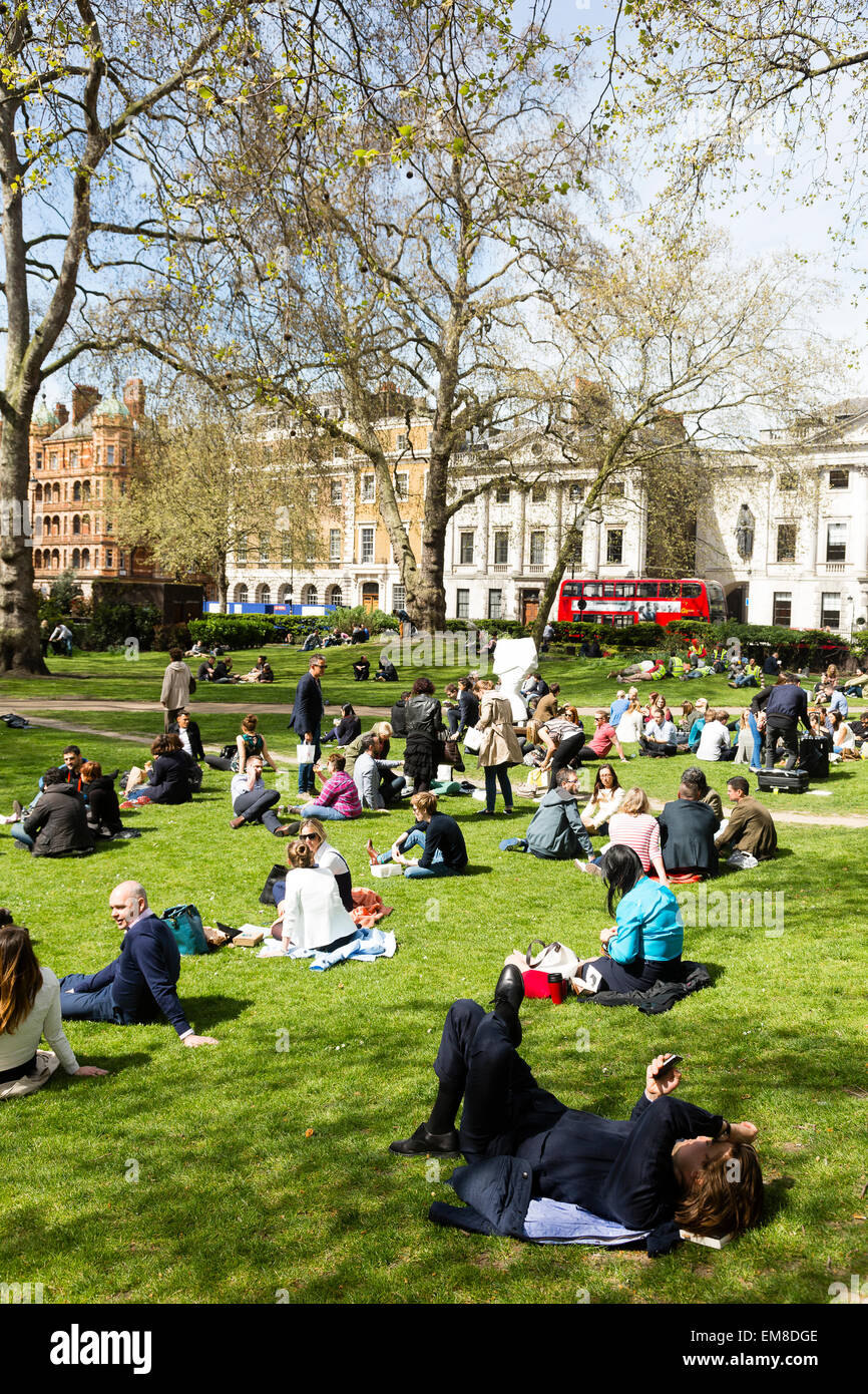 London, UK. 17. April 2015. Ein Mann liegt auf dem Rasen im Cavendish Square Gardens prüft sein Telefon in eine entspannte Mittagspause. Bildnachweis: Dave Stevenson/Alamy Live-Nachrichten Stockfoto